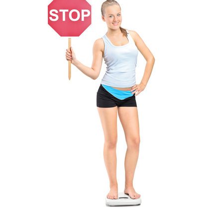 Why Pediatricians and Parents Should Wait to Talk Weight with Teens Girl on scale holding stop sign