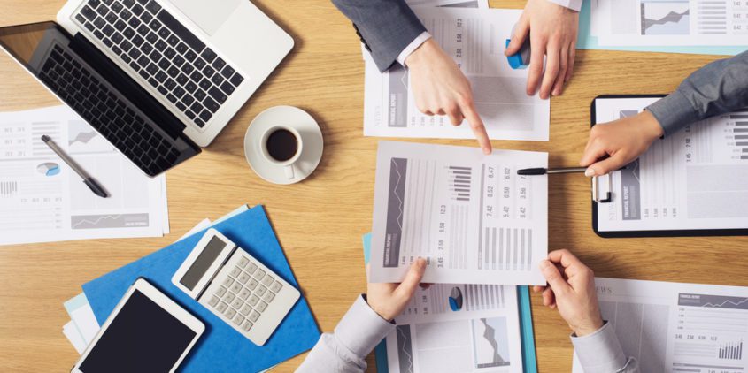 Are You Running These 3 Essential Practice Management Reports? Business people around a table with computers and financial reports