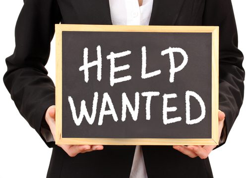 Close-up image of a man holding a Help Wanted chalkboard sign
