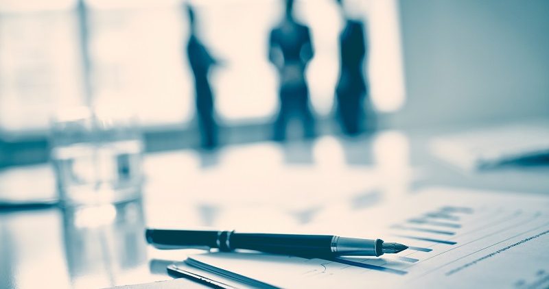 8 Tools to Help a Pediatric Practice Become a Successful Business Fountain pen on business document, three men standing on background