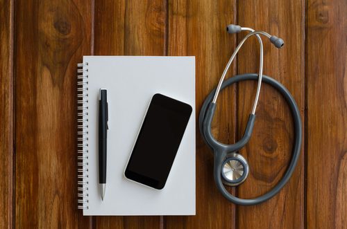 PCC 2016 Users' Conference Highlights Mobile Phone on Notebook with Pen next to Stethoscope