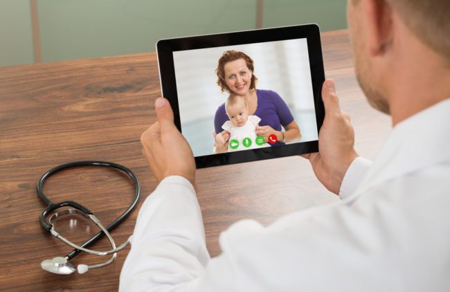 12 Reasons To Choose A Pediatric-Specific EHR Doctor communicating with mother and child on a tablet.