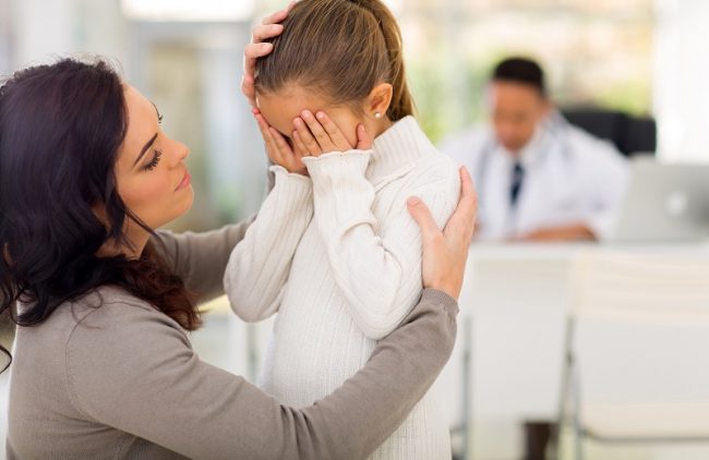 Public Violence: How a Pediatrician Can Help loving mother comforting her sick daughter in doctor's office