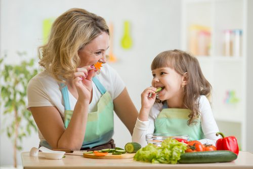 Considering Pediatric PCMH? 8 Things You Should Know woman and young girl cooking together with fresh vegetables
